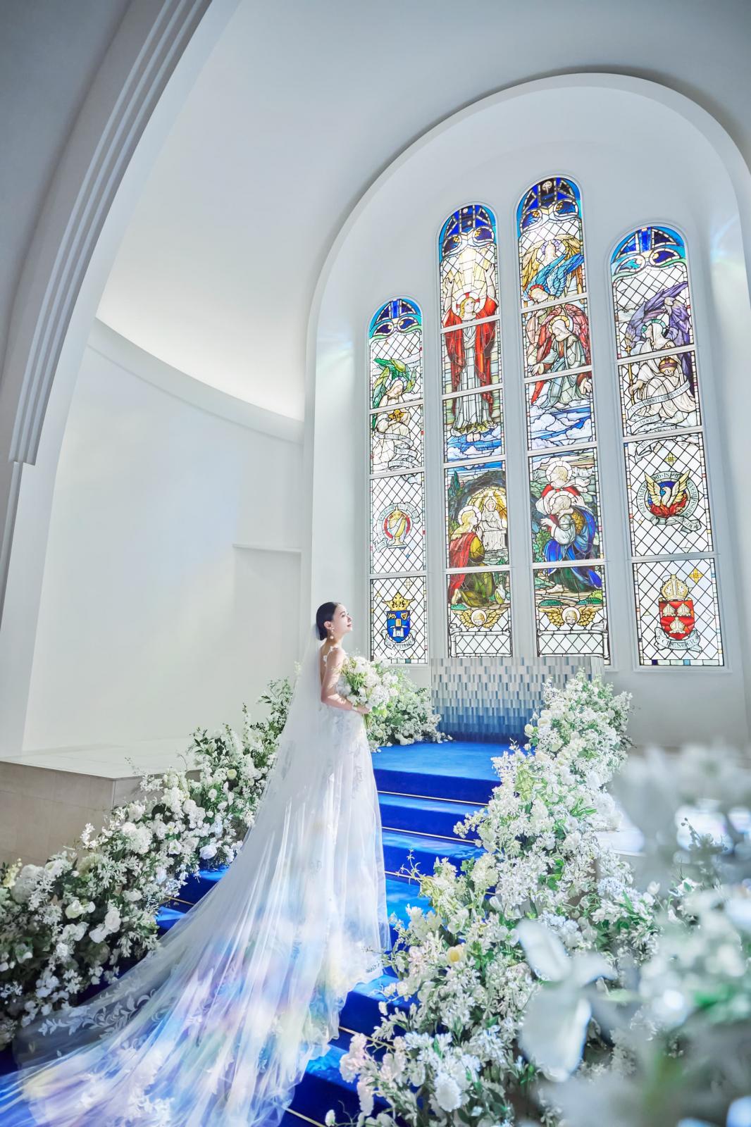 ロイヤルブルーのバージンロードとステンドグラスが花嫁をより美しく輝かせます