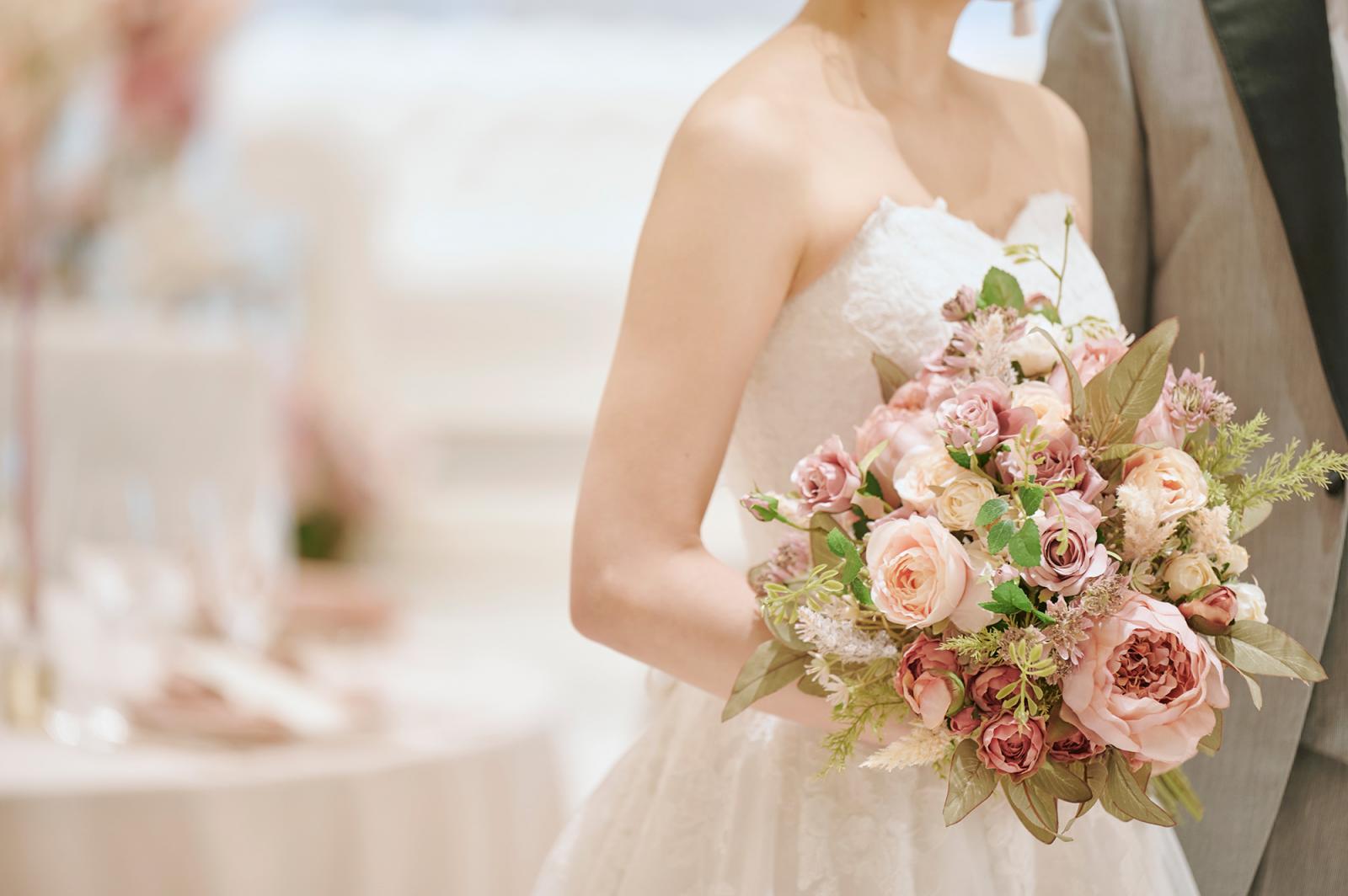 幸せを象徴するようなブーケをいつも手に。会場コーディネートに合わせた濃淡ピンクが肌映えする