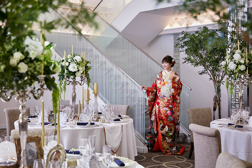 艶やかな色打掛を纏って。しっとりとした絹を埋め尽くすように描かれた大輪の花や鶴。職人の手仕事が息づく