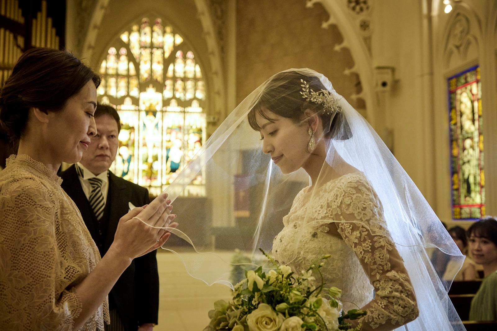 花嫁の身を守ると伝わるウエディングベールをおろし挙式へ。エレガントなレースが花嫁を美しく包む