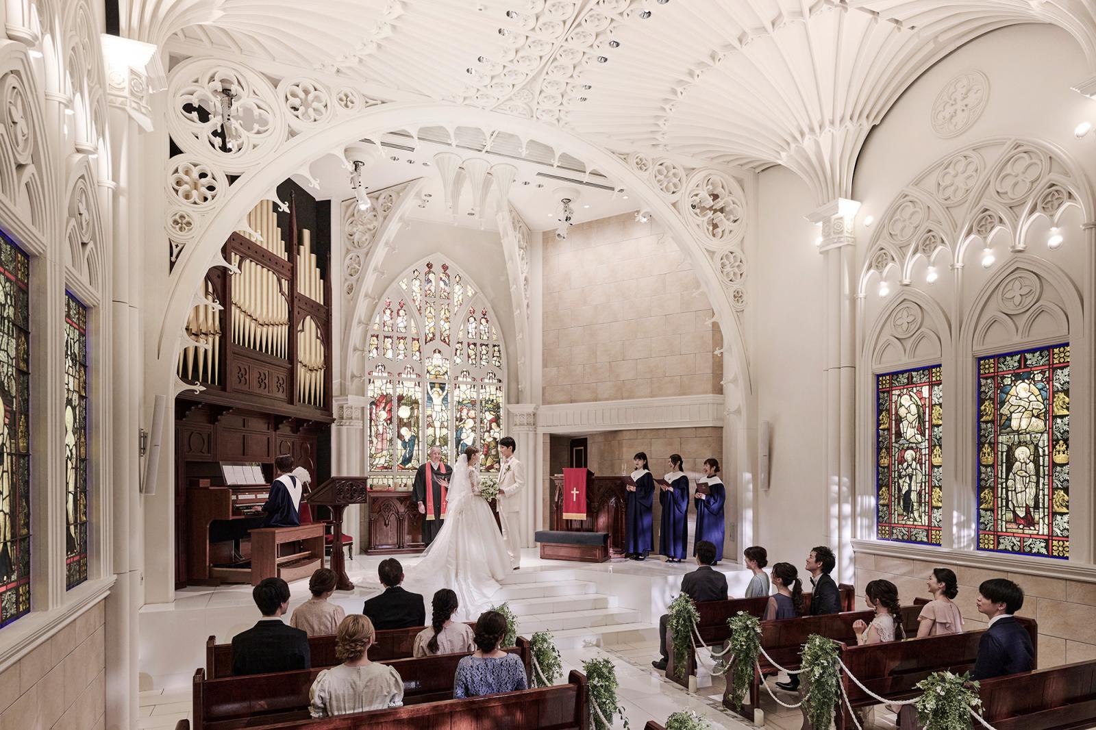 重厚なパイプオルガンの音色に導かれて挙式が始まる。祭壇は少し高くなっているのでどのゲストからもふたりが見える