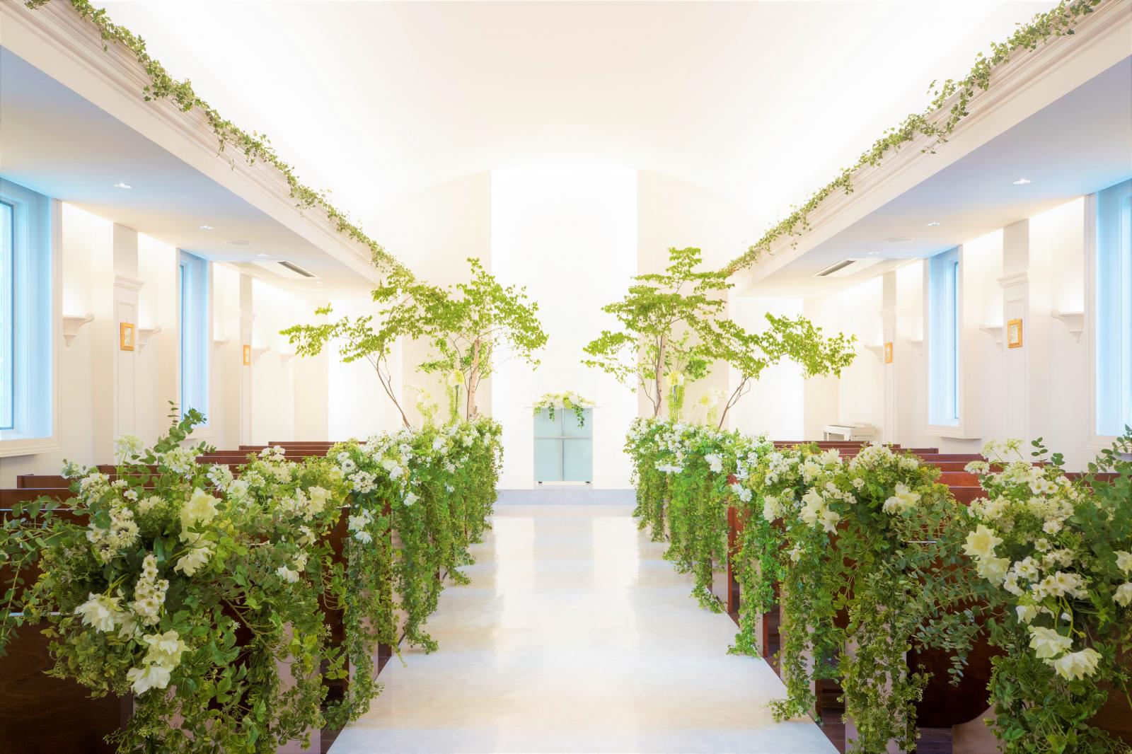 天井高５ｍ。開放的な空間にあたたかな自然光が差し込む。ヴァージンロードや祭壇には花や木々の色味で鮮やかに彩られ、お二人の門出を華やかに祝福してくれる。