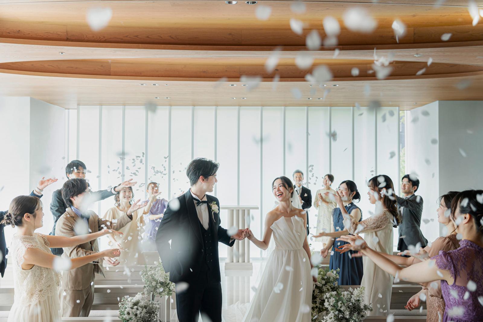 ゲストからの祝福の花びら舞うフラワーシャワー。あたたかな距離感で笑顔弾ける時間。