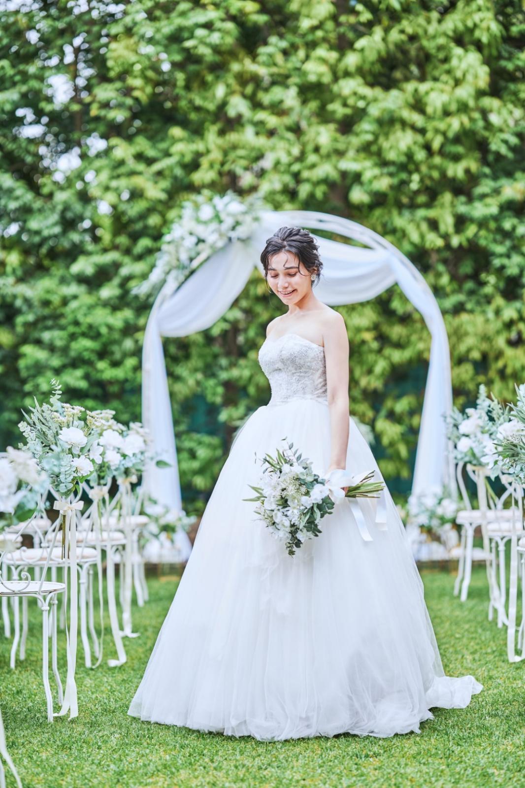 柔らかな自然光に照らされ、溢れる緑が純白のウェディングドレスのシルエットを引き立てる