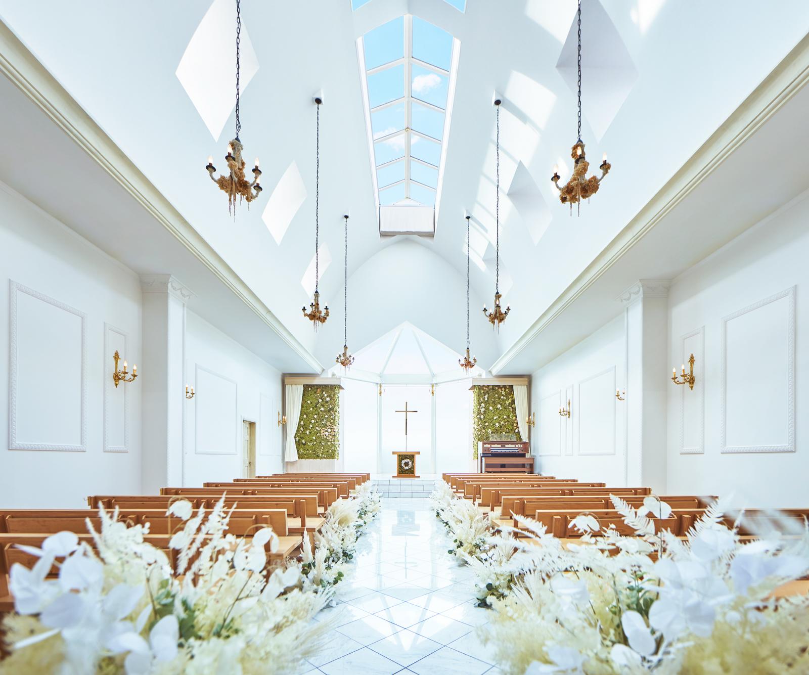 高さ8ｍもの天井から降り注ぐ柔らかな陽光に満ちた、自然と調和した優しい空間に。オリーブの木を用いたベンチや緑のコーディネートが温もりを感じるナチュラルな教会。