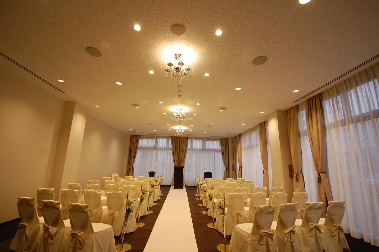 純白のドレスに身を包んだ新婦様　ゆっくりと歩まれる　真っ白なバージンロードの先には　新郎様　光り差し込む開放的な空間のなかでゲストに見守られながら　特別は空間を演出