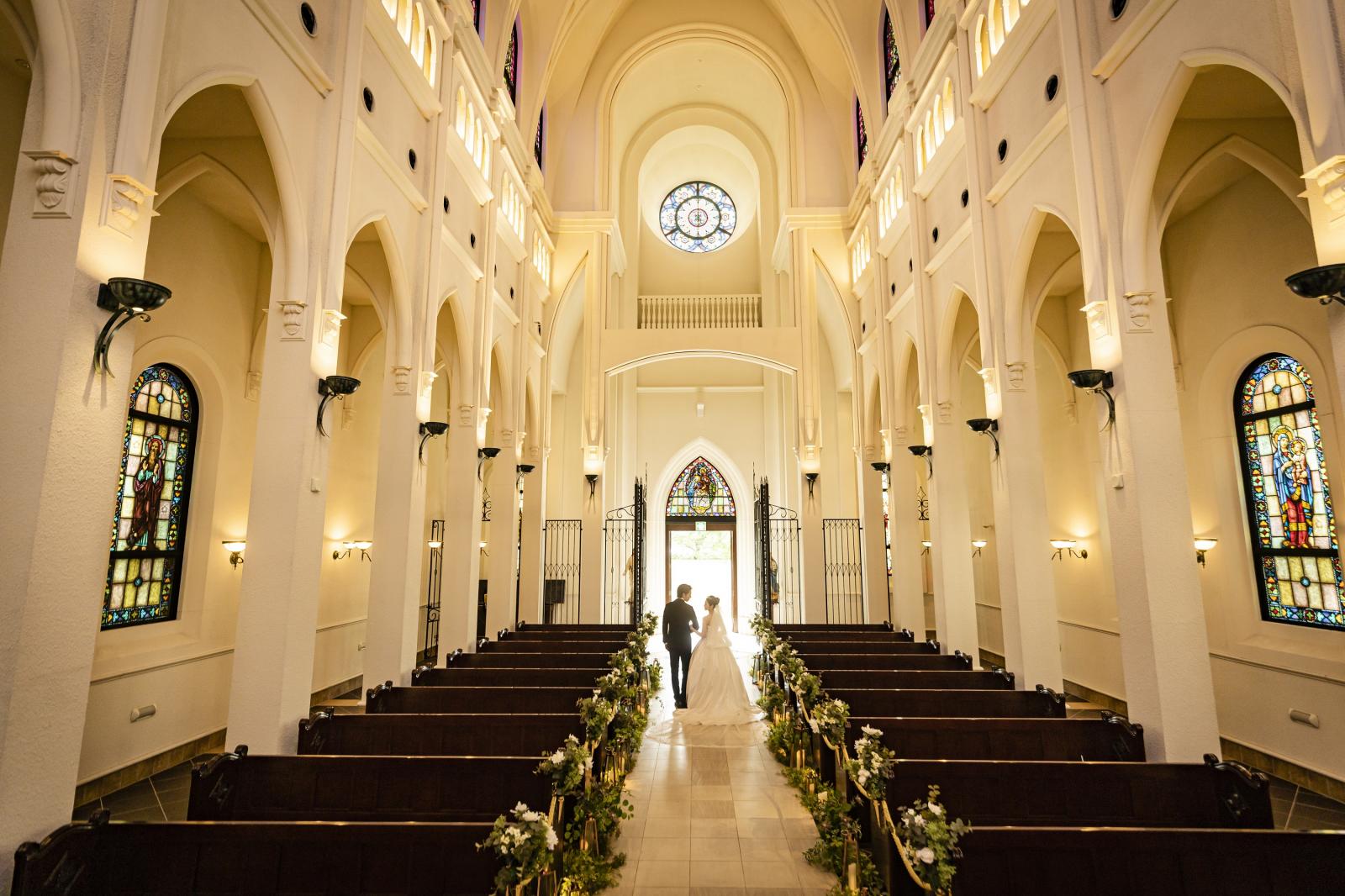 退場シーンでは扉を開いた瞬間、逆光が飛び込んでくる。光に包まれるように退場するシーンは感動的。ドレスの裾が綺麗に広がったまま歩けるように、バージンロードの幅も通常の教会の1.5倍ほどある。