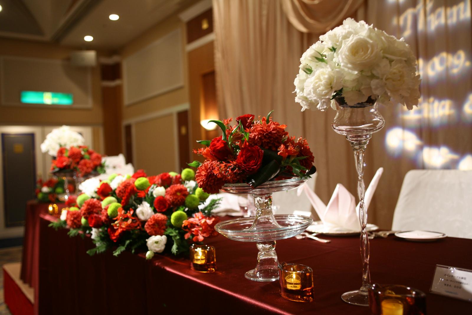 ダイヤモンドホール　メインテーブル　ワインレッドのクロスにホワイト・レッド・グリーンのお花が映える。
