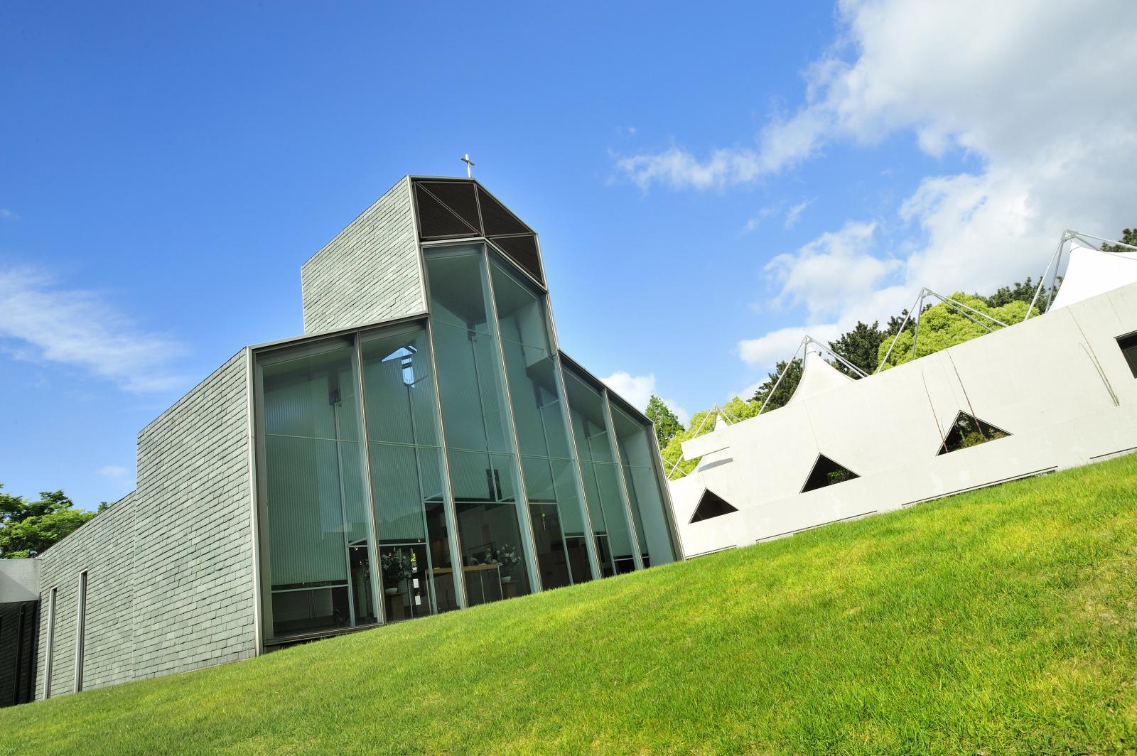 緑の芝生に佇む独立型チャペル、前面がガラスで太陽の日差しが純白のバージンロードを映し出しす。