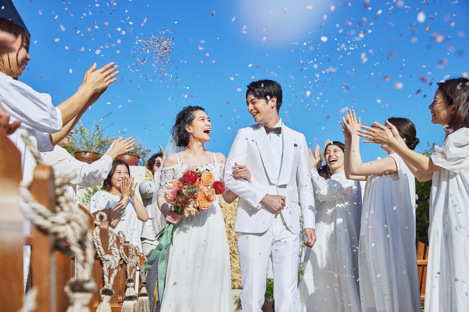 挙式の緊張がほどけたら外の空気へ。祝福の花びらが舞い笑顔とシャッター音が交差する<br />
ブレパーティの時間