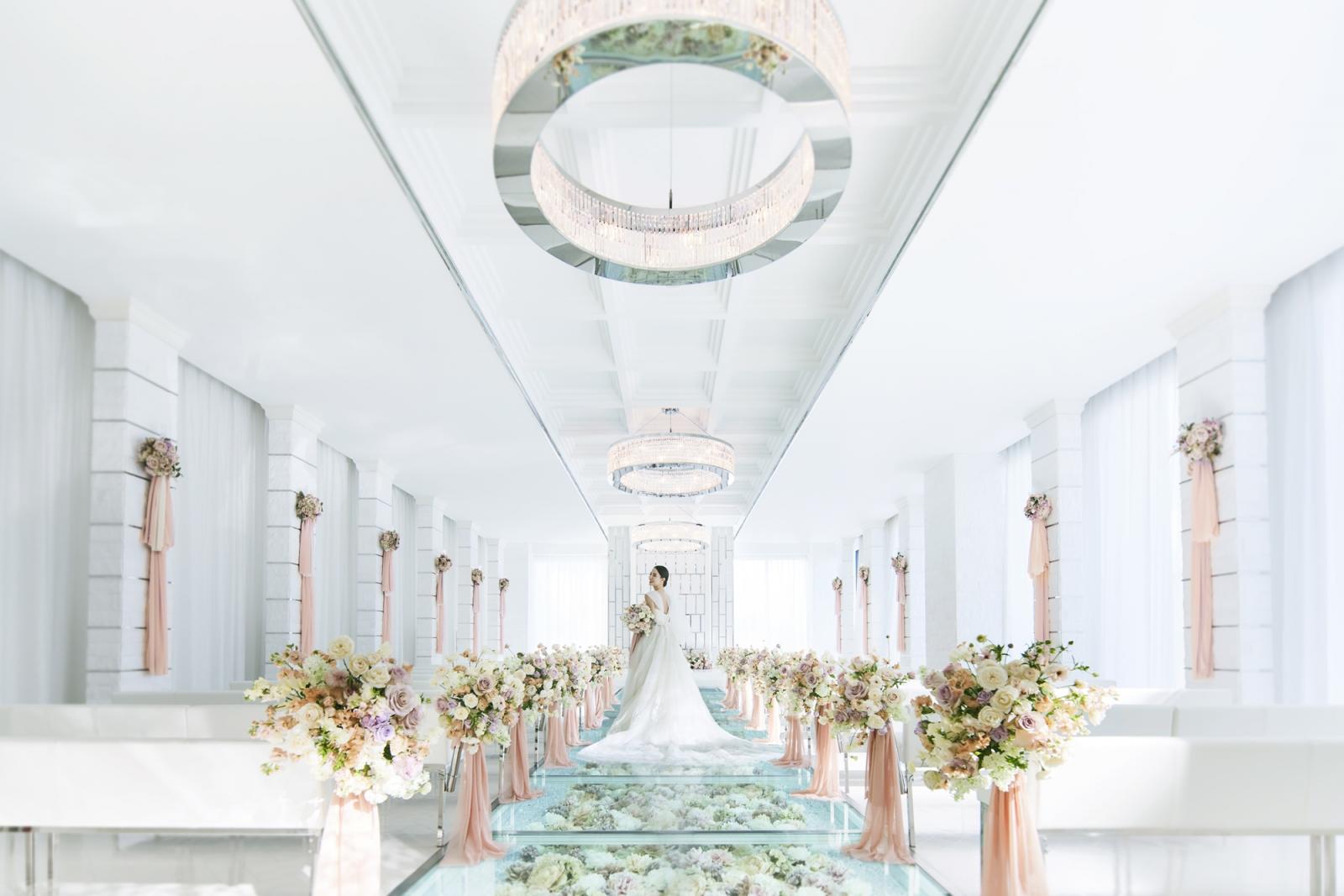 白基調の空間にフラワーバージンロードが彩りをそえる。全天候型チャペルだから天候に左右されず、理想の挙式が思いのまま