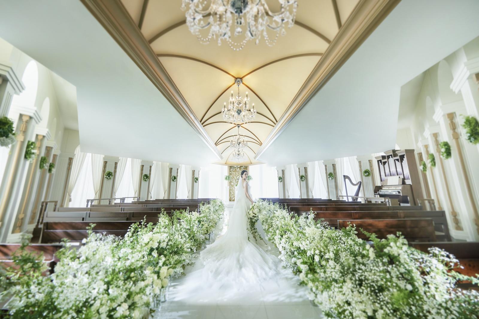 射し込む光にキラキラと反射する天井のクリスタルシャンデリアが幻想的。優雅なホテルのような上質感が漂うナチュラル×ラグジュアリーな挙式空間で感動のひと時を。