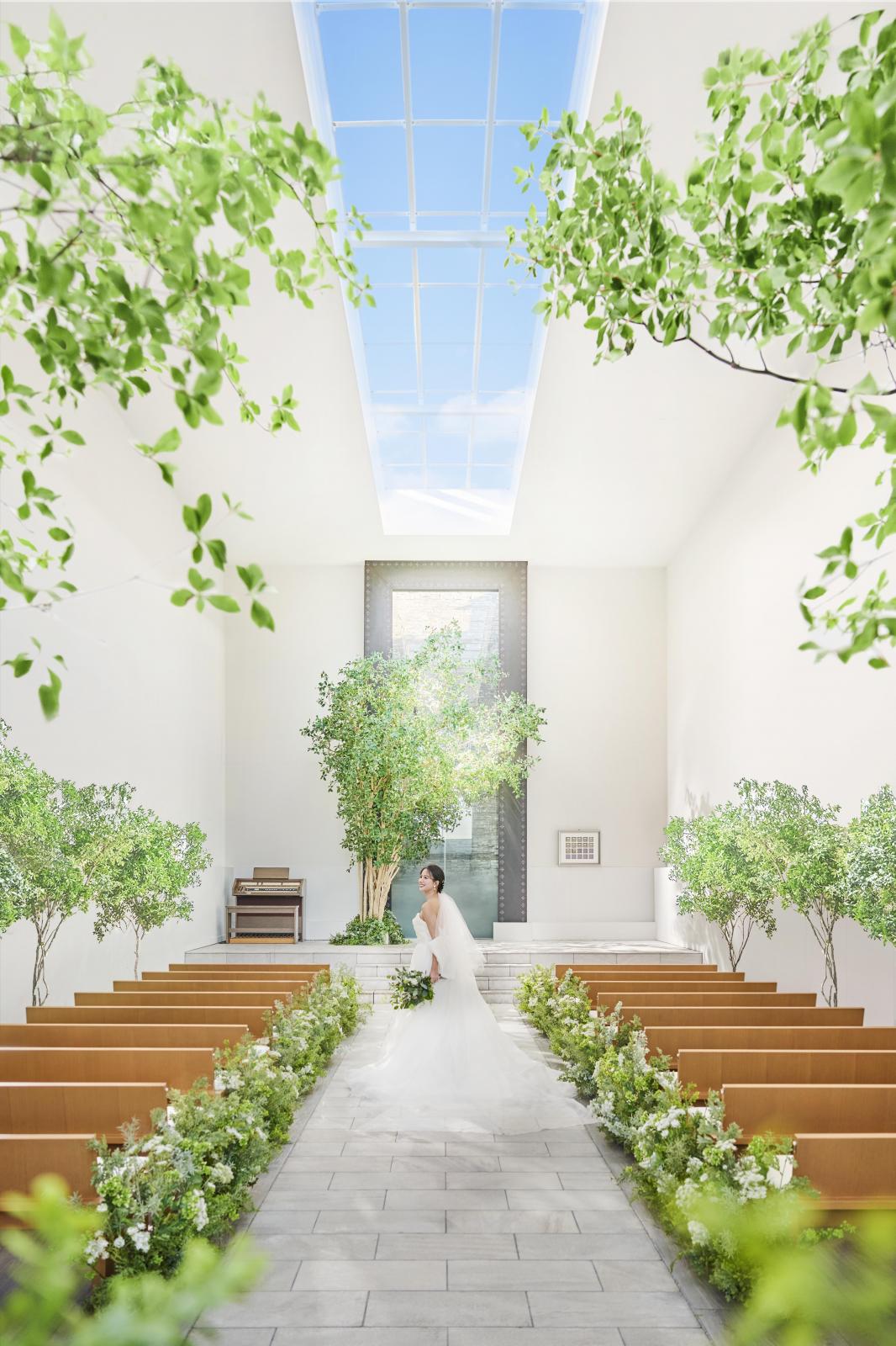 シンボルツリー「ガジュマル」を背景にしたチャペルは純白のウエディングドレスが映える+*